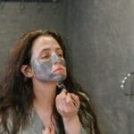 Kobieta nakłada maseczkę na twarz w nowoczesnej łazience