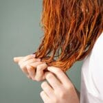 Zbliżenie na zadbane rude włosy trzymane delikatnie w dłoniach