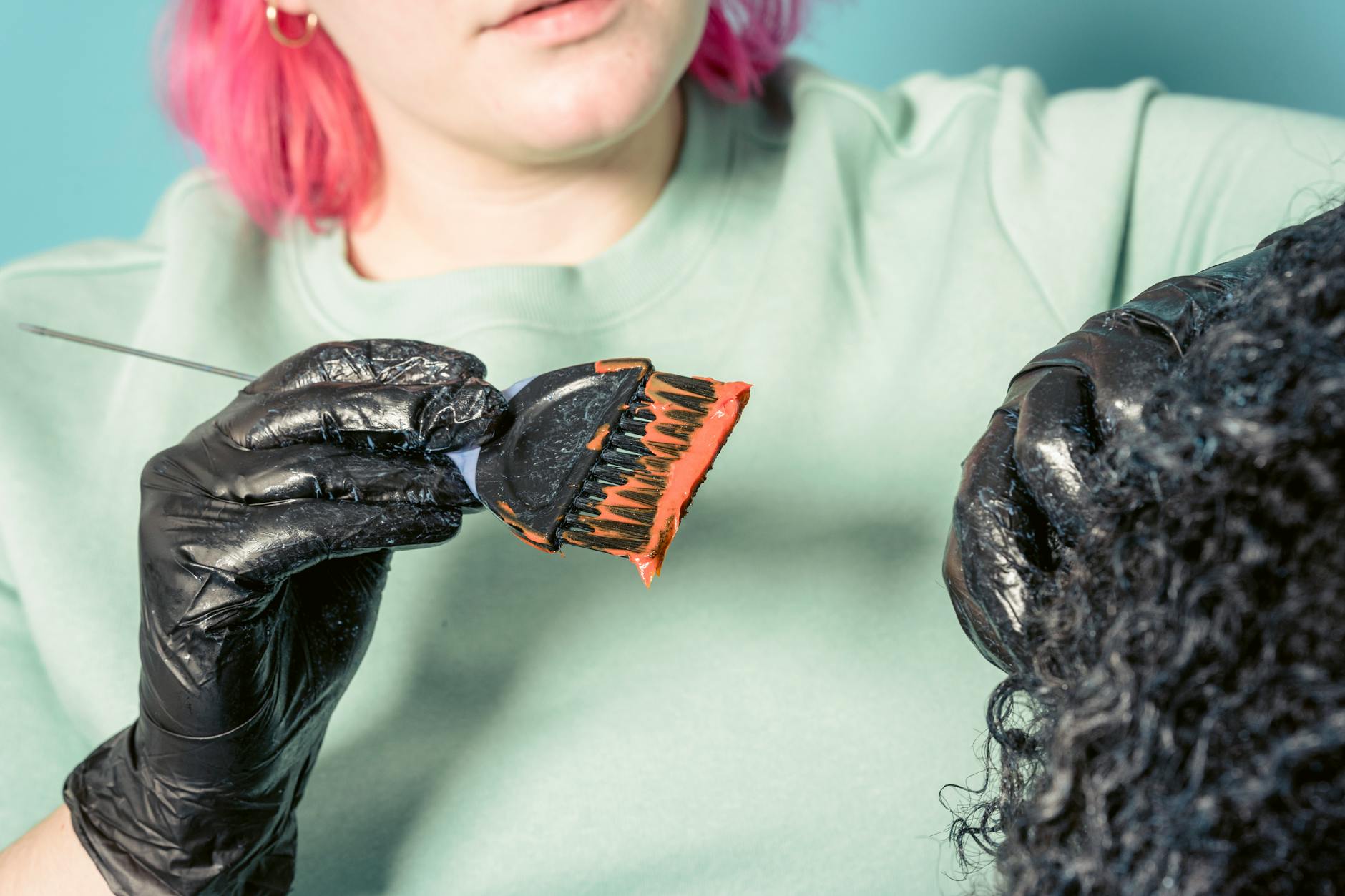 Fryzjerka nakłada farbę na kręcone włosy klientki w salonie