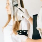 Fryzjerka nakłada farbę na włosy klientki metodą z folią