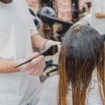 Fryzjerka nakłada farbę na włosy klientki w salonie